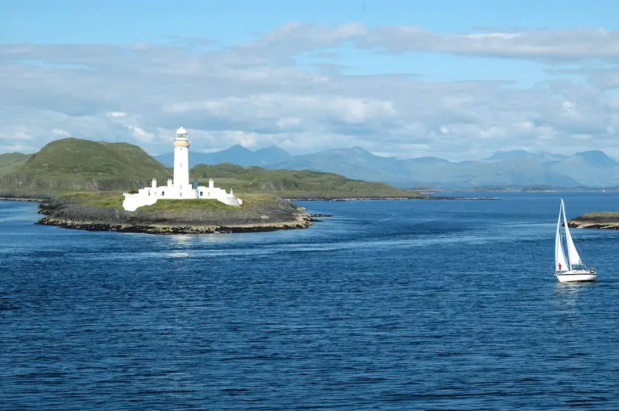a sailboat in a body of water near a lighthouse